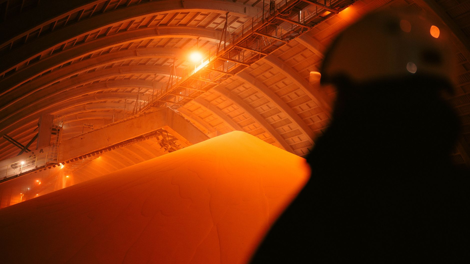 Silhouetted worker in an orange-lit industrial facility in Libya.