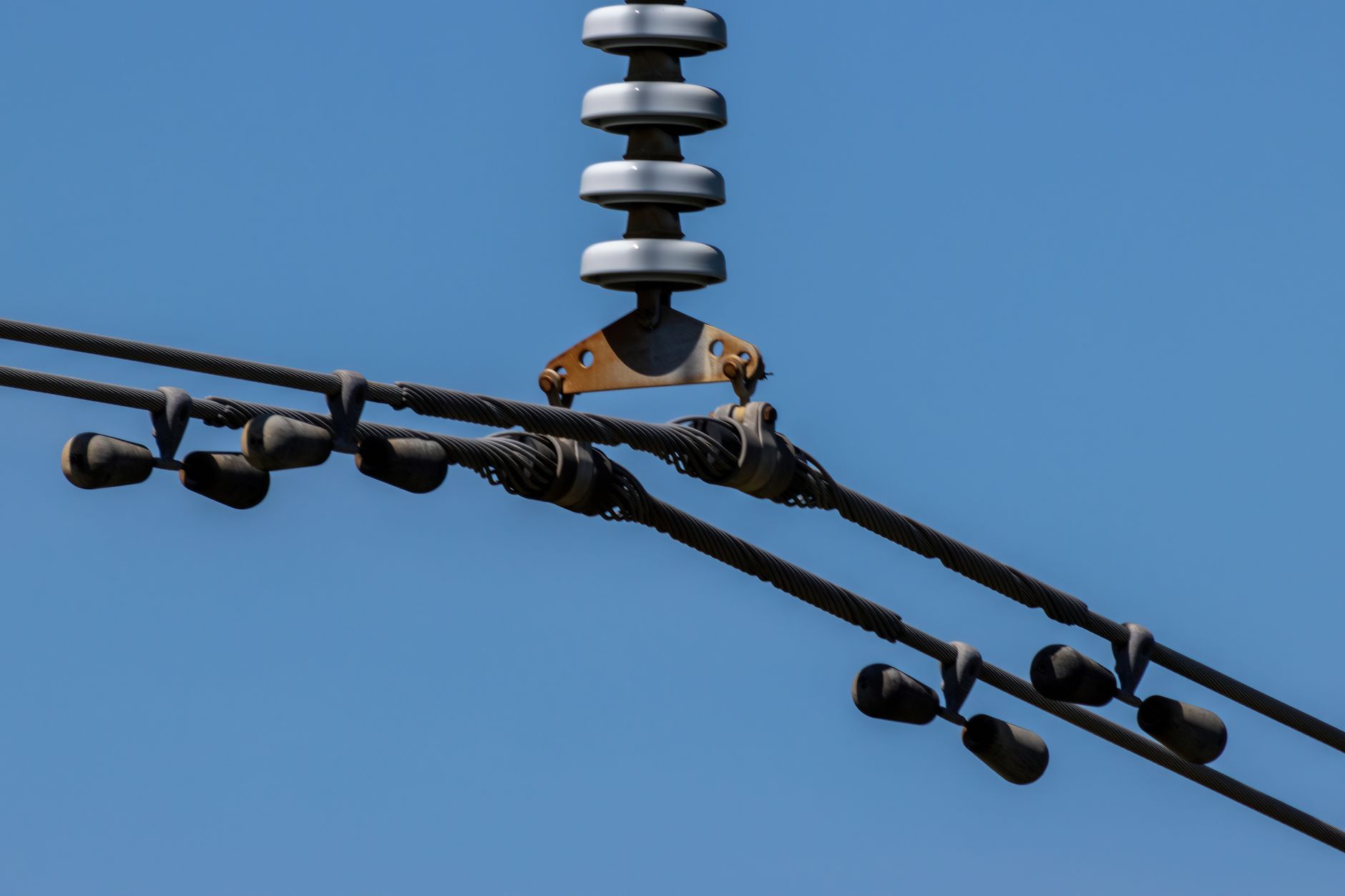 Detailed view of overhead power lines with blue sky background. Ideal for energy themes.