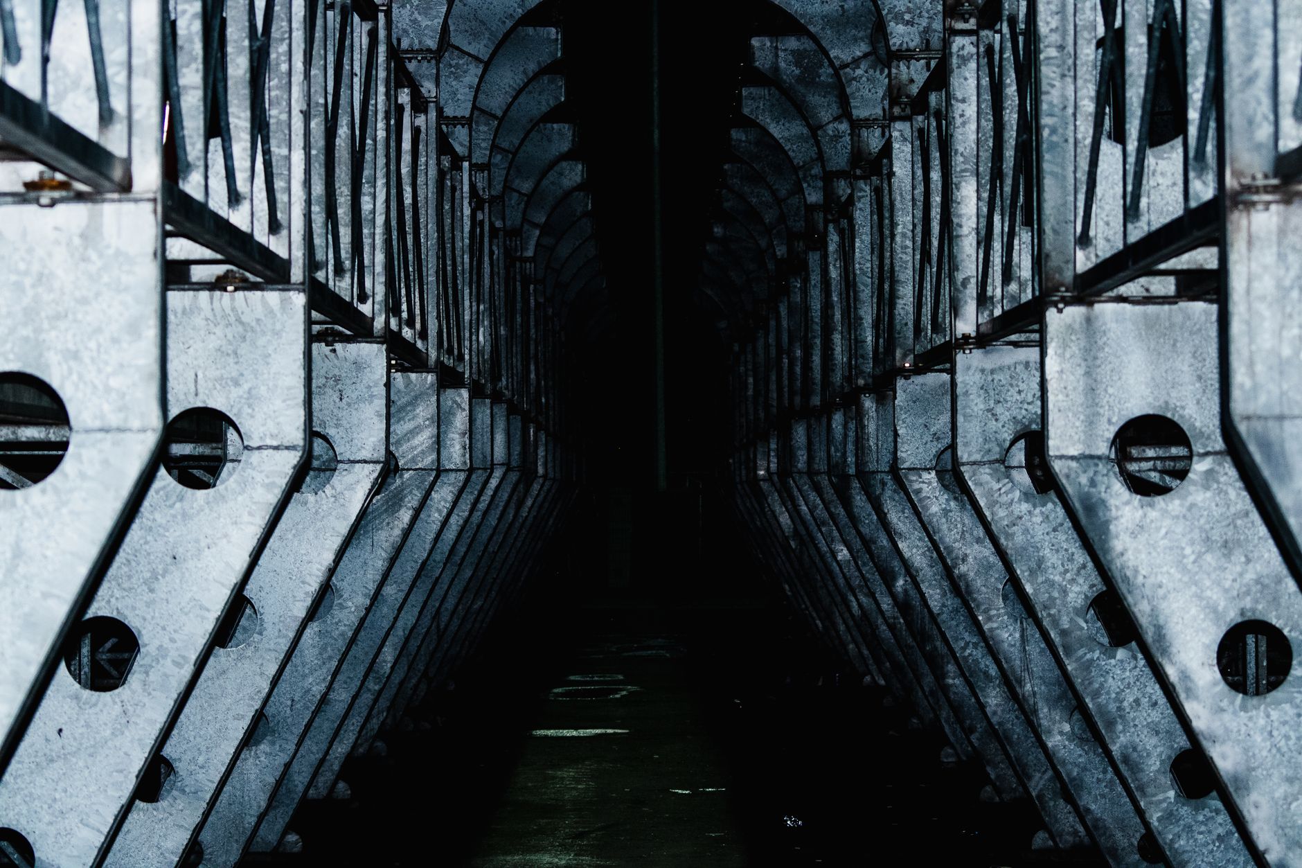Dark and dramatic night shot of an industrial metal structure with geometric patterns under shadowed lighting.