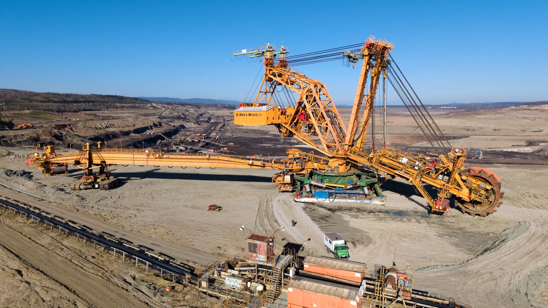 Aerial view of a giant excavator at work in a vast open-pit mining landscape.