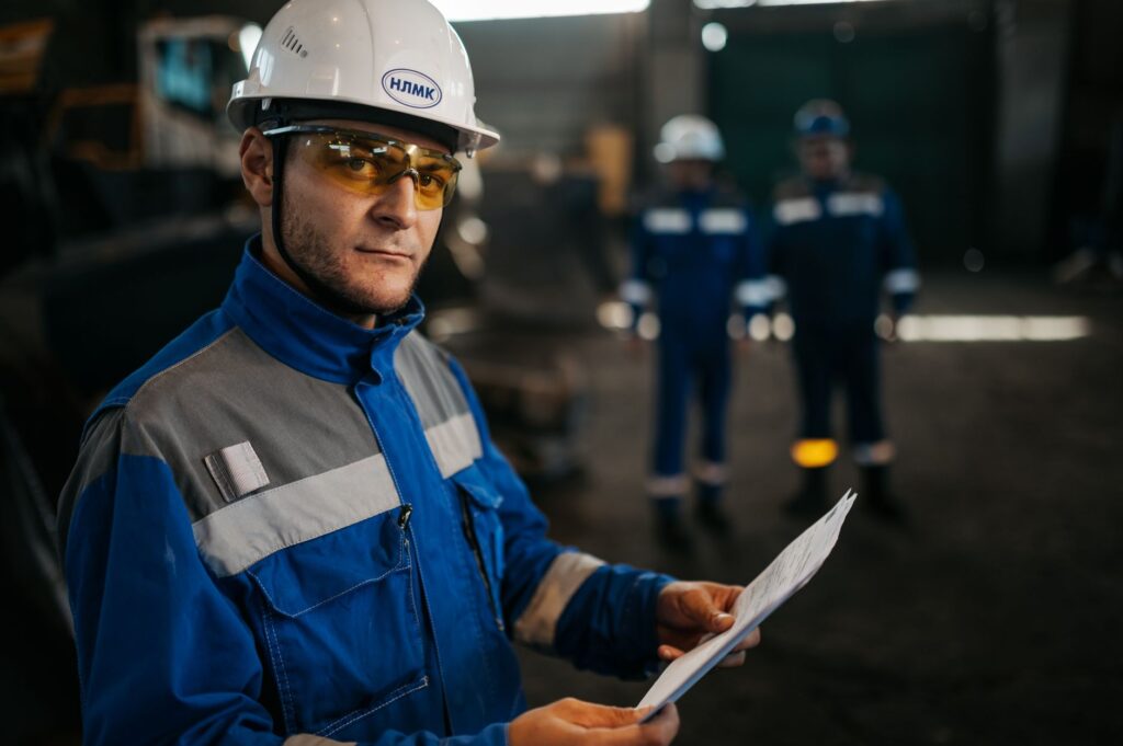 Focused industrial worker in protective gear reviewing documents in a factory setting in Russia.