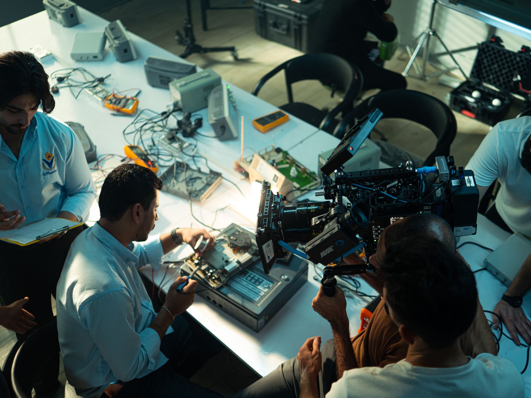 Film crew capturing technicians working on electronics repair in Baghdad, Iraq.