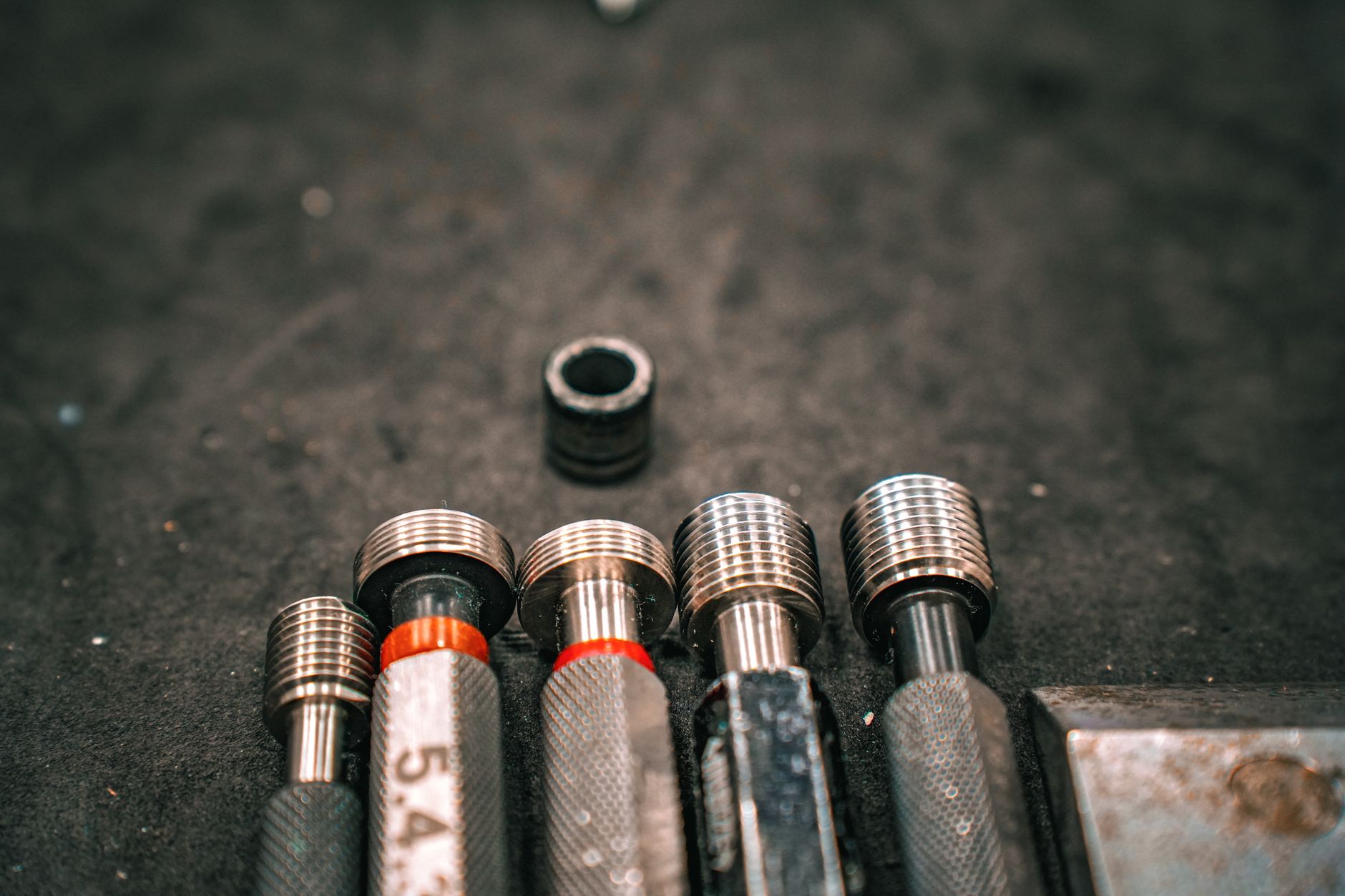 Detailed macro shot of metal industrial tools aligned on a gritty surface.
