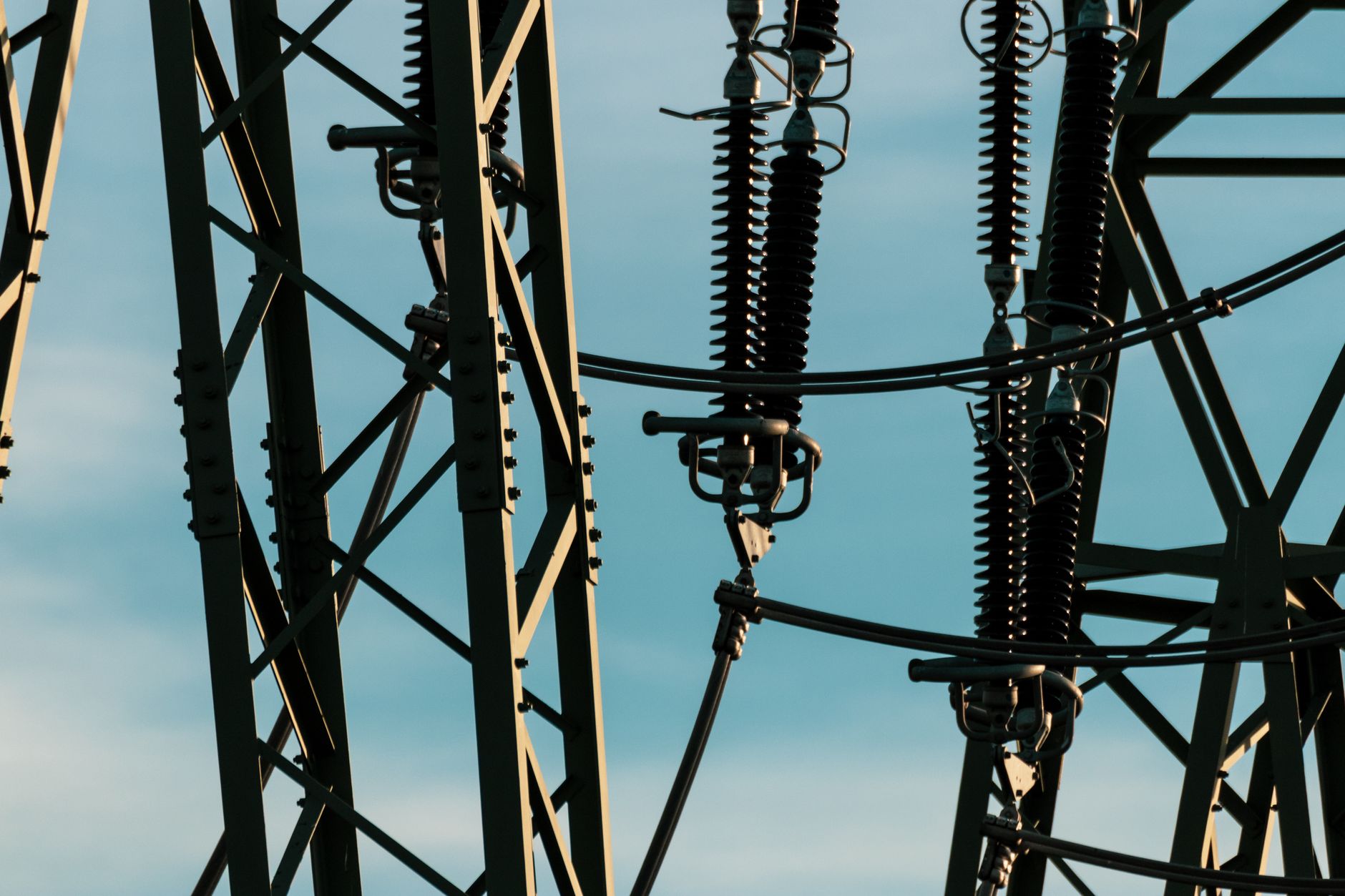 Detailed shot of power lines and electrical insulators set against a vivid blue sky.