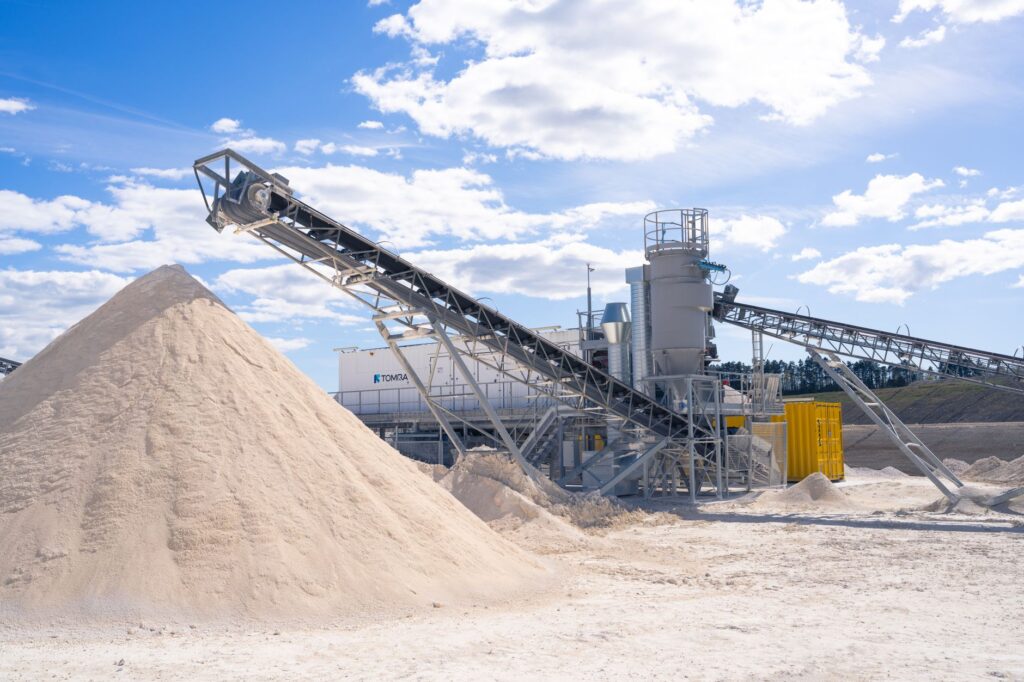 A modern sand processing plant with conveyor belts under a clear blue sky.