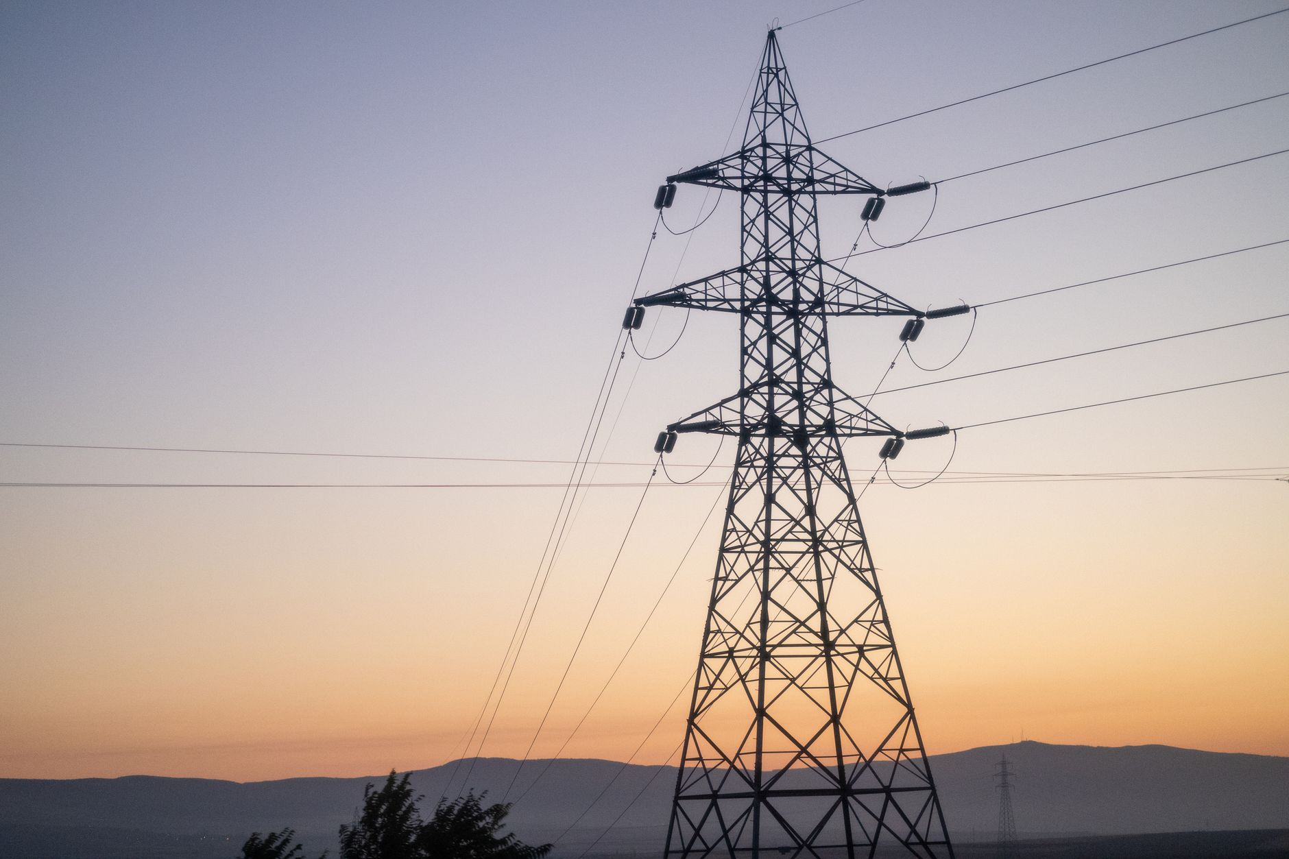 High-voltage power lines silhouetted against a vibrant sunset sky in Eskişehir, Türkiye.