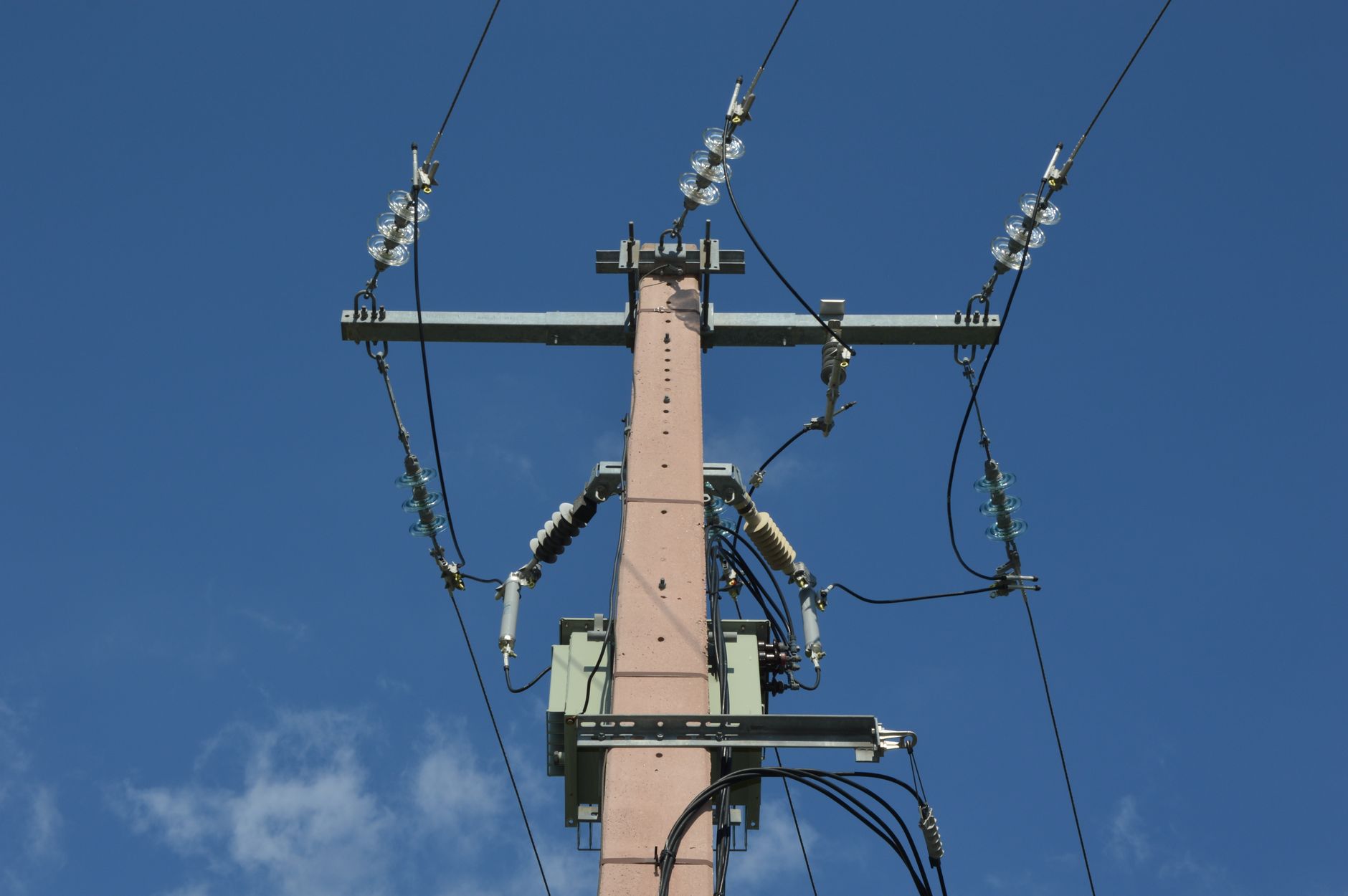 Low angle view of a utility pole with power lines against a blue sky.