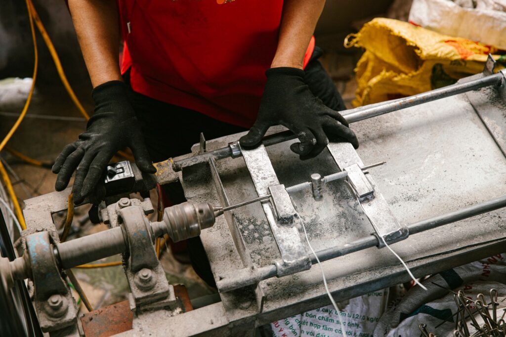 Worker in red shirt using machinery with precision in an industrial setting.