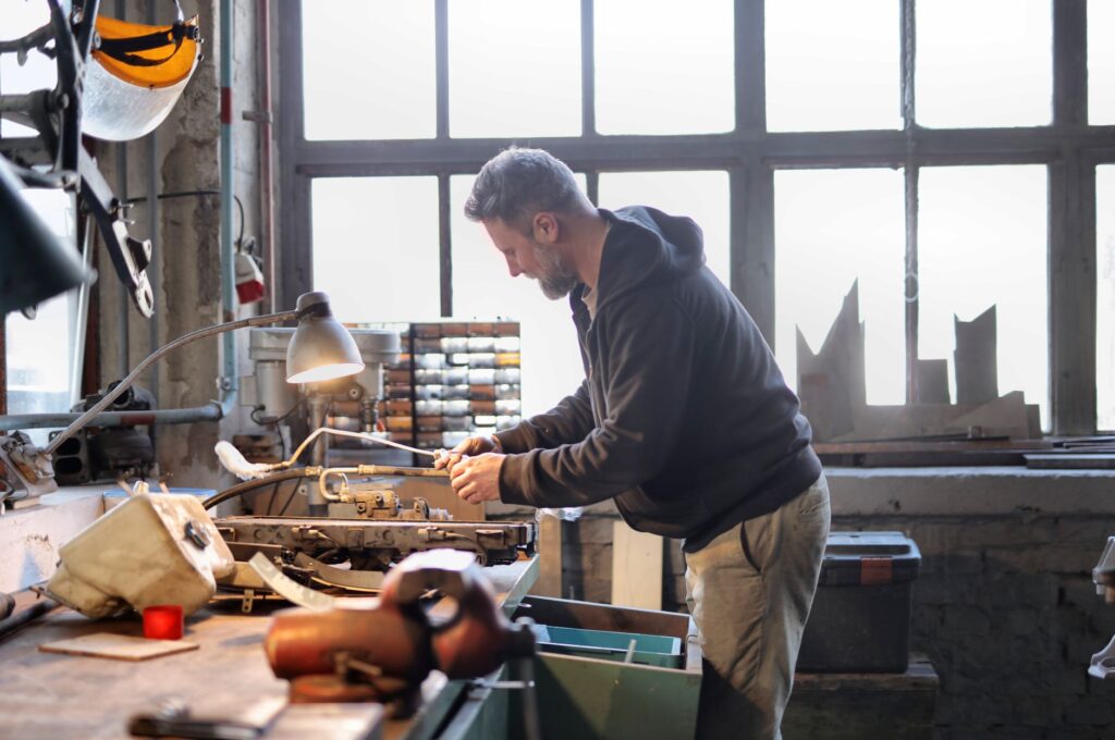 Experienced craftsman skillfully repairing equipment in a spacious and light-filled workshop.