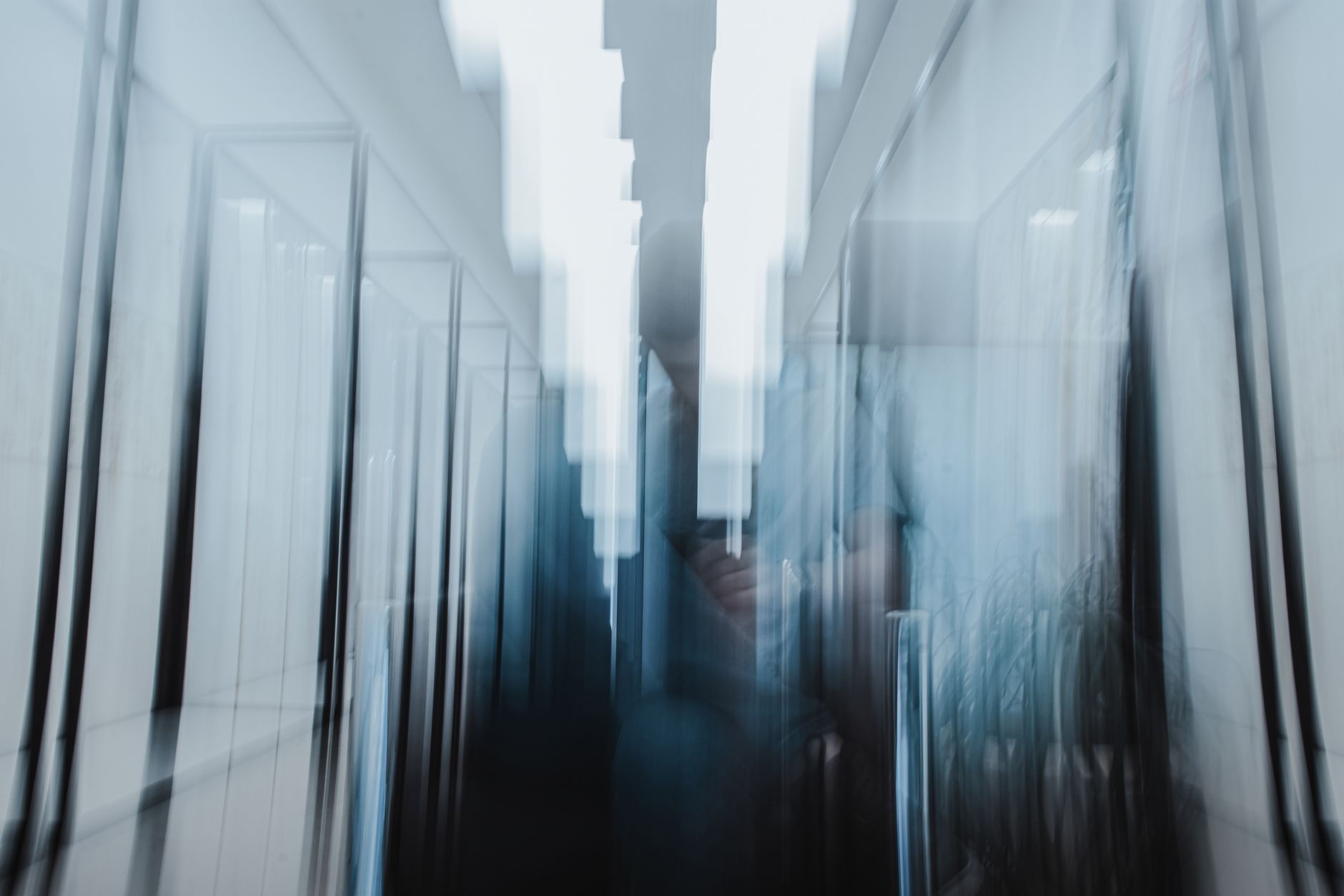 Abstract image showcasing motion blur in a modern hallway with glass and steel architecture.