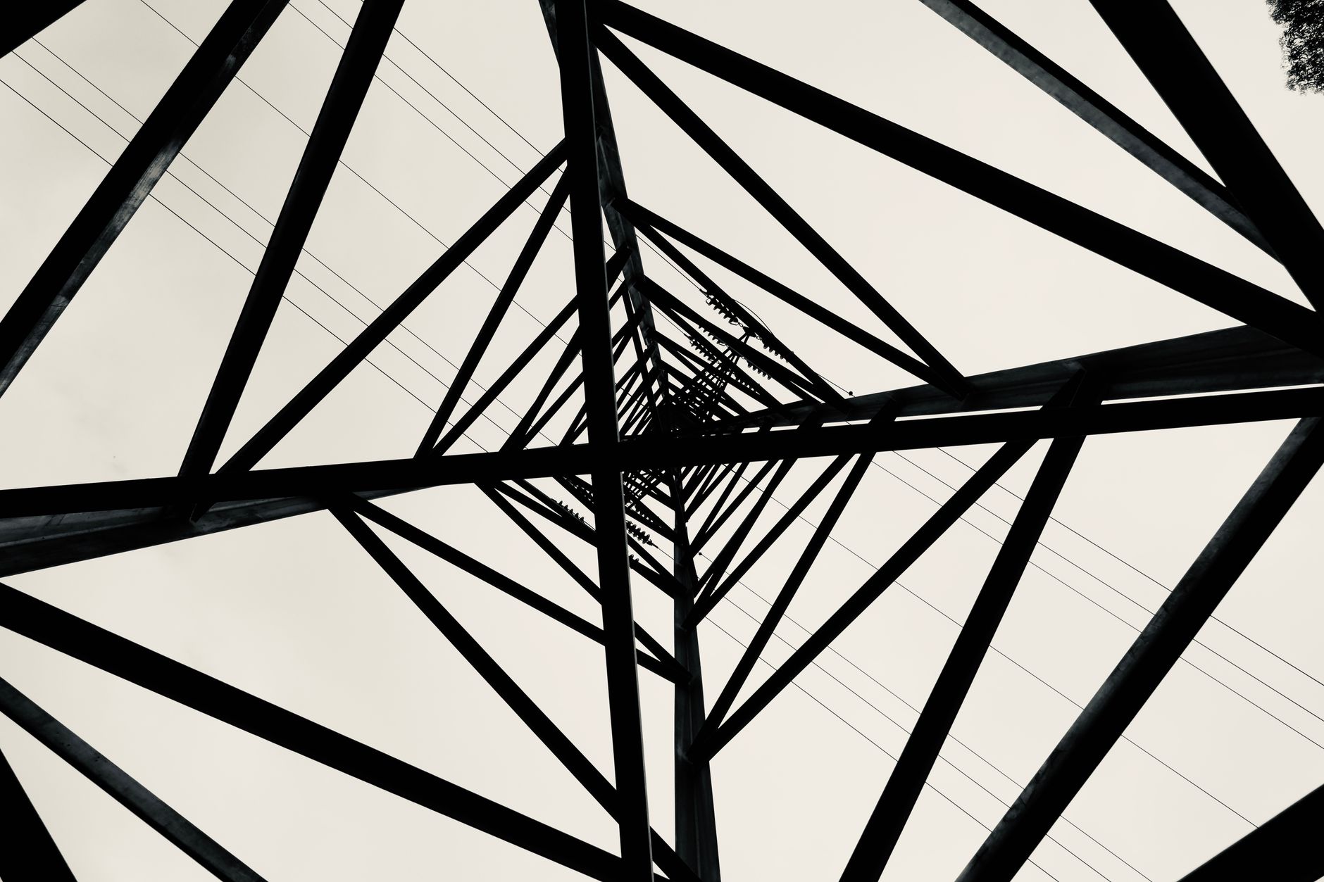 Black and white low angle shot of a transmission tower showcasing geometric patterns.